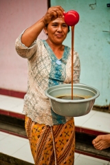 Ibu Juli proudly showing her fresh palm syrup, produced on a wood fire.